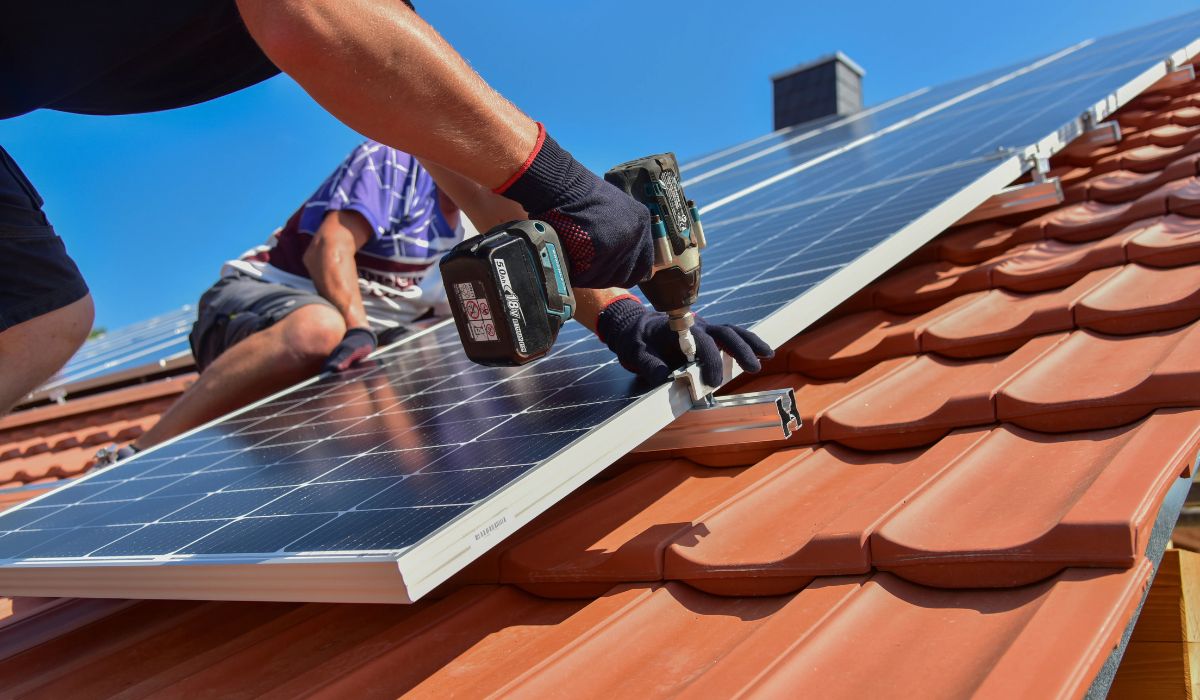 Monteur installiert Solarmodul auf Ziegeldach