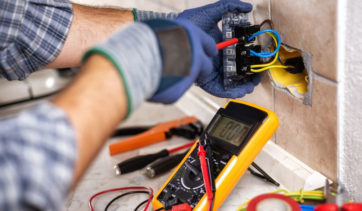 Elektriker installiert Steckdose mit Multimeter